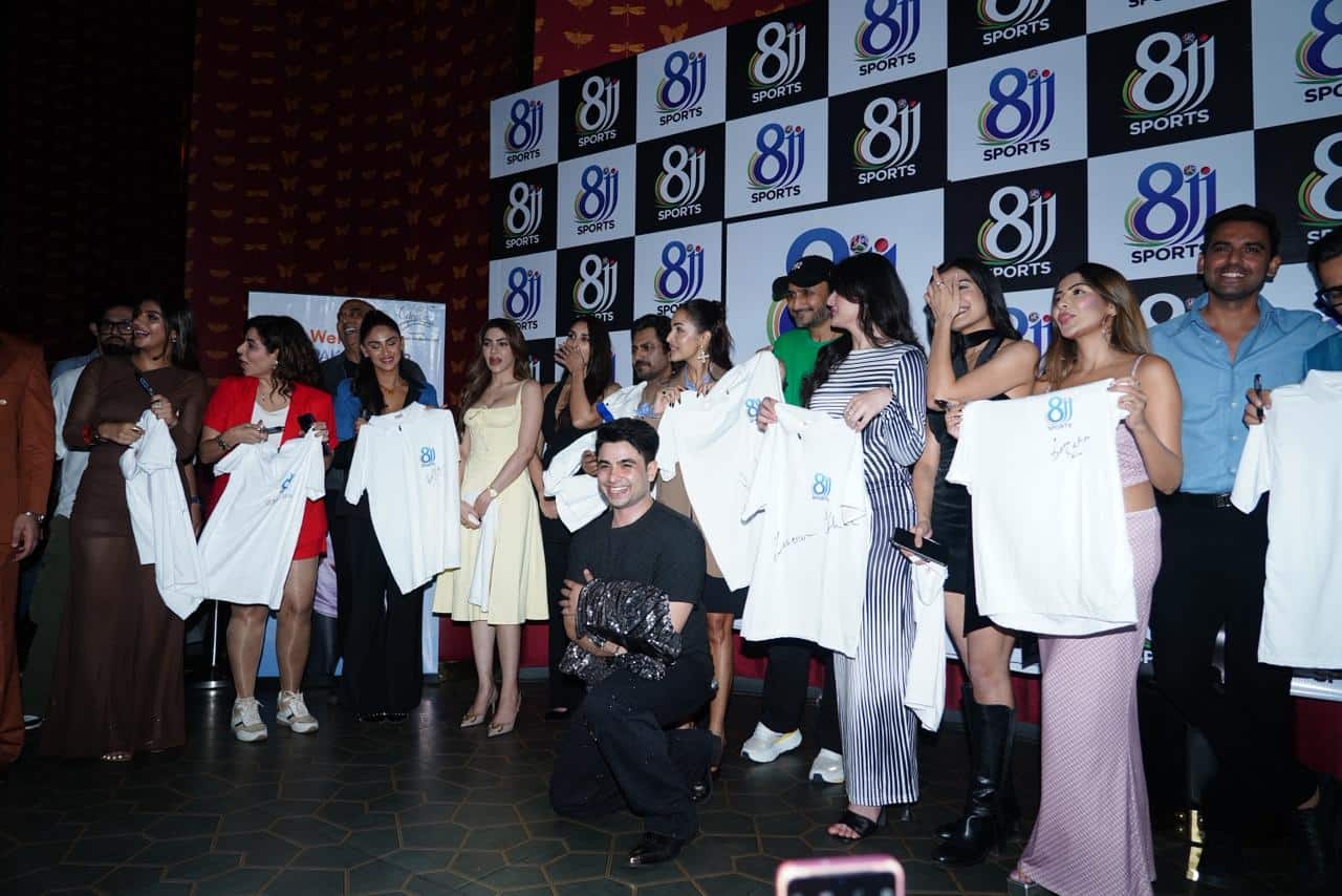 Cricket players group photo at sports event with signed merchandise and branding backdrop.